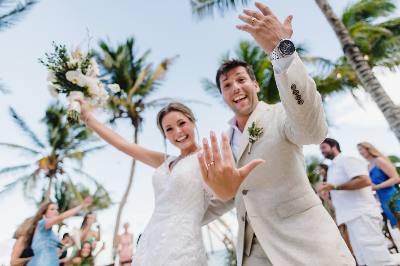 happy couple show to their wedding photographer in riviera maya the brand new rings happy to be married under the blue sky and pamtrees